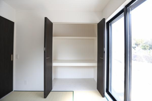 横尾東町1丁目1期2号棟の浴室|浴室には清潔感のある白を基調とした内装が施されています。壁面の木目調が落ち着いた雰囲気を演出しています。ミラーや収納棚も備わっており使い勝手の良い設計です。