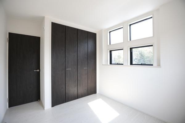 横尾東町1丁目1期2号棟の洋室|大きな窓から自然光がたっぷり入り明るく開放感のある洋室です。クローゼットが備え付けられており収納スペースも確保されています。木目調のドアやクローゼット扉が空間に落ち着いた印象を与えます。