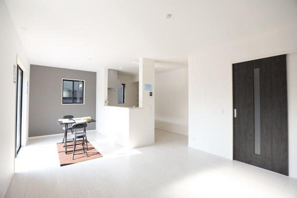 横尾東町1丁目1期2号棟の居間・リビング|リビングは大きな窓から自然光がたっぷり入る明るい空間です。白を基調とした内装が広々とした印象を与えます。隣接するキッチンが使いやすいレイアウトです。室内はすっきりとした仕上がりになっています。