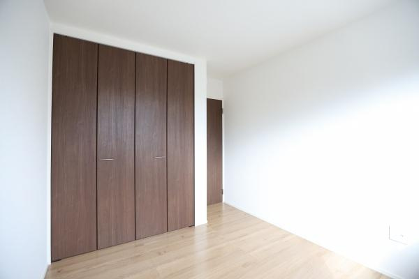 徳島2丁目1期3号棟の収納|木目調の扉が印象的な収納スペースです。ハンガーポール付きで衣類の整理も快適に行えます。床までしっかりスペースが確保されています。扉は開閉しやすい設計です。