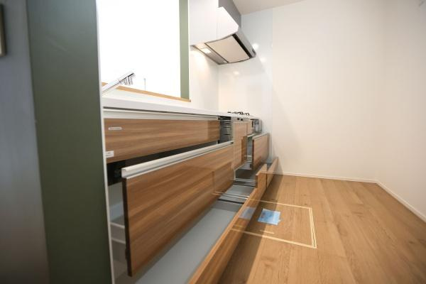 徳島2丁目1期3号棟のキッチン|木目調のデザインが特長的なキッチンです。収納スペースがしっかり確保されています。カウンター付きで作業しやすい仕様です。ガスコンロが設置されていて操作も簡単です。全体的に清潔感のある雰囲気です。