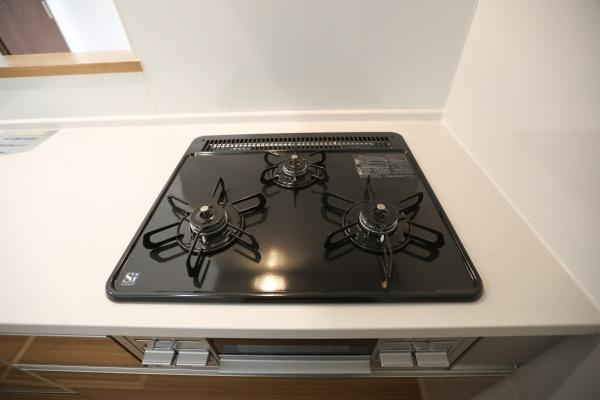 徳島2丁目1期3号棟のキッチン|木目調のパネルがアクセントとなっているキッチンです。スッキリとした直線的なデザインが特徴です。引き出し収納が豊富で整理がしやすい仕様です。作業スペースが広めに確保されています。