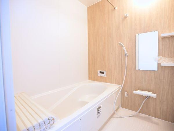 挾間町下市2期9号棟の浴室|木目調パネルが印象的な空間です。バスタブが広めでリラックスしやすい印象です。設備が整っておりシンプルなデザインが使いやすそうです。ミラーや棚など必要な設備も揃っています。