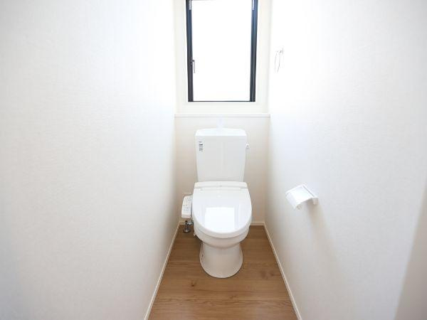 挾間町下市2期9号棟のトイレ|清潔感あるシンプルな内装が印象的です。窓付きで自然光が入るため明るく開放的な空間となっています。床には木目調が採用され落ち着いた雰囲気が漂います。壁紙は白を基調としており清潔感が際立ちます。
