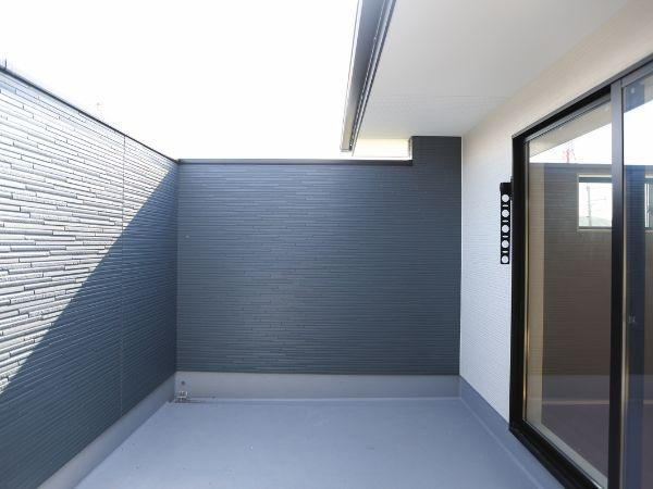 挾間町下市2期9号棟のバルコニー|プライバシーが保たれた空間が広がるバルコニーです。壁面は落ち着いた色合いでまとめられており周囲からの視線を遮ります。スライドドアで室内と一体感があります。ゆとりある広さが特徴的です。