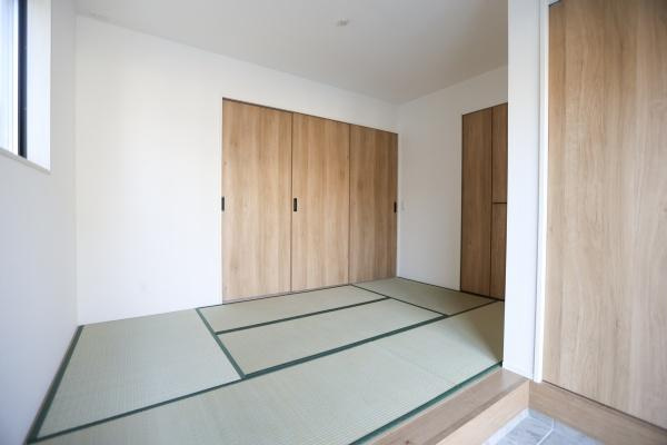 挾間町下市2期9号棟の和室|シンプルな内装で落ち着いた雰囲気の和室です。大きな窓から自然光が入り明るさを感じられます。木目調の収納扉が空間にやさしい印象を与えます。収納スペースも十分に確保されています。