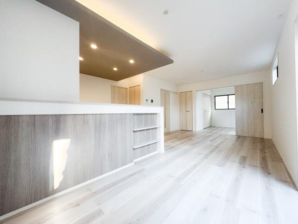 羽屋4丁目1期1号棟の居間・リビング|木目調の床とカウンターが空間に落ち着きを与えます。天井のダウンライトが明るさを演出しています。開放感のある広々としたリビングです。リビングには収納棚も備わっています。