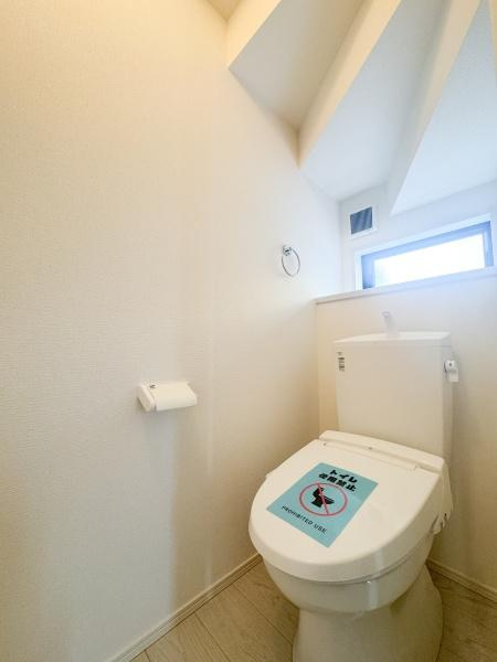 大字森町3期1号棟のトイレ|白を基調としたシンプルな内装で清潔感のあるトイレスペースです。窓があるため換気や採光も良好です。無駄のないすっきりとした空間が魅力です。天井部分のデザインもアクセントになっています。