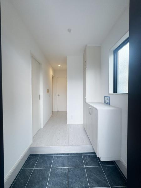 大字森町3期1号棟の玄関|白を基調とした明るい玄関はすっきりとした印象です。シンプルなデザインで空間が広く感じられます。窓からの自然光が採り入れられており室内がより明るくなっています。収納スペースもしっかり確保されています。