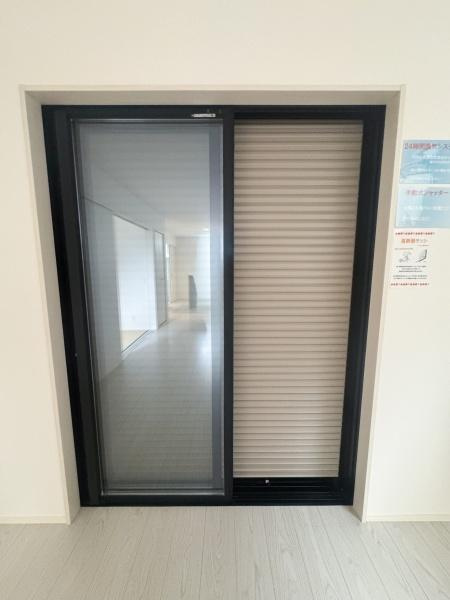 大字森町3期1号棟の居間・リビング|リビングに設置された大型の窓は開放感を演出します。シャッター付きで外部からの視線を遮ることができます。シンプルなデザインが空間に調和しています。ガラス部分が広く明るい印象を与えます。