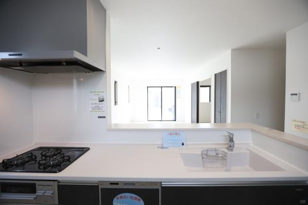 大字荏隈2期2号棟のキッチン|明るい空間が広がるキッチンです。シンプルなデザインで作業スペースもすっきりとしています。カウンター付きで開放感があります。ガスコンロとシンクの配置も使いやすいレイアウトです。
