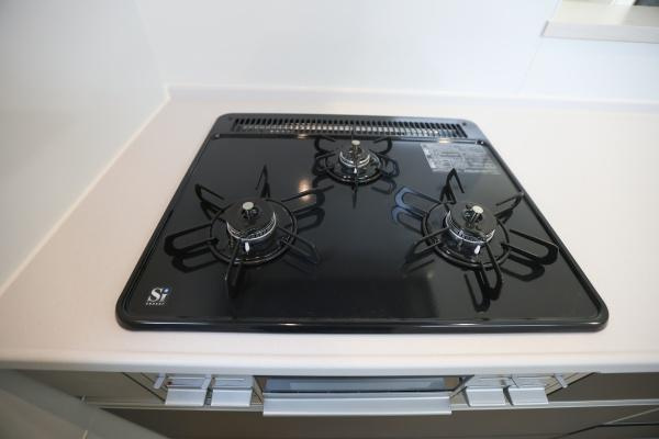 大字荏隈2期2号棟のキッチン|スタイリッシュなガスコンロが設置されています。3口仕様で効率よく調理できます。作業スペースも広々としており使い勝手が良いキッチンです。掃除のしやすいフラットな天板もポイントです。