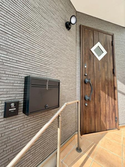 【玄関】 | 木目調の玄関ドアが印象的な外観です。便利なポストとインターフォンが設置されています。タイル張りのアプローチでお手入れしやすいです。手すりが配置され安全面にも配慮されています。