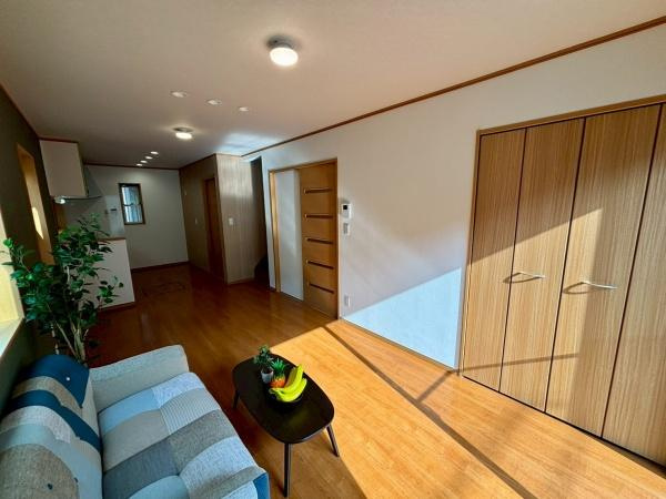 【居間・リビング】 | リビングには大きな窓がありたっぷりと日差しが入ります。床やドアの木目が空間全体に温かみを与えています。収納スペースも充実しておりすっきりとした印象です。レイアウトがしやすい広さも魅力です。