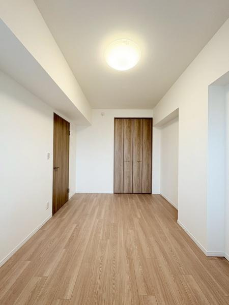 ルネ戸塚弥生台の居間・リビング|洋室７．２帖・ウッド調の扉が白色のクロスと調和して落ち着いた空間に。凹凸を利用して絵画を置いても、デスクスペースにも。