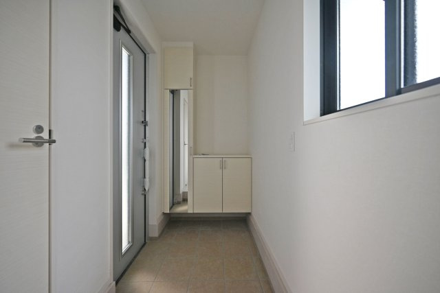 尼崎市武庫町3丁目新築一戸建て3号棟│4LDK+駐車1台可の玄関|シューズボックスは空間に合わせた白を採用。どんな飾りにも合うためインテリアや思い出の品で彩って、ゲストを気持ちよくお迎えできます。また全身鏡がついているため、外出前に身だしなみを整えることができます。