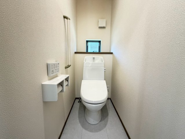 静岡市葵区田町７期　新築戸建　全７棟　A号棟のトイレ|小窓付きで圧迫感を抑えた、すっきりと清潔感のあるトイレ。手すりも備わっており、使いやすさにも配慮されています。