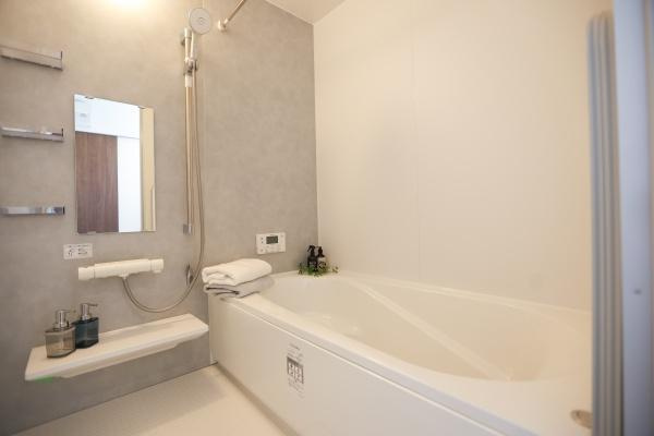 中鶴崎Ｗ　新築の浴室|壁面には鏡や棚が設置されており使い勝手の良い設計です。浴槽はゆったりとした形状でリラックスできます。小物置きスペースも充実しています。