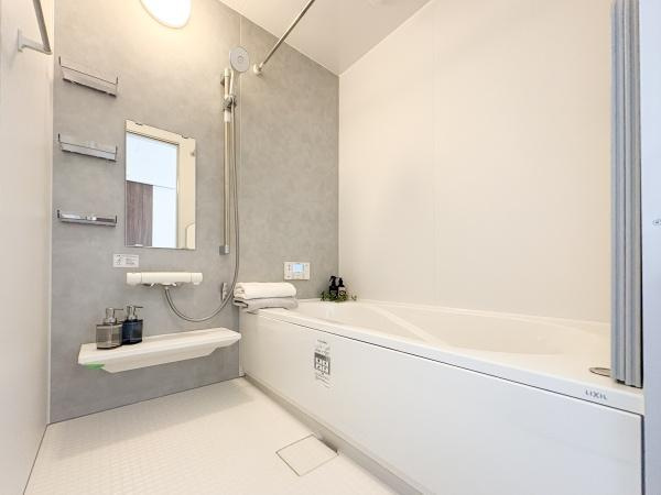 中鶴崎Ｗ　新築の浴室|壁面には鏡や棚が設置されており使い勝手の良い設計です。浴槽はゆったりとした形状でリラックスできます。小物置きスペースも充実しています。