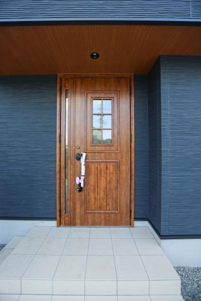 中鶴崎Ｗ　新築の玄関|ナチュラルな木目調の玄関ドアが印象的です。広々としたタイルのアプローチはすっきりとした雰囲気を演出します。シンプルなデザインが外観全体によく調和しています。