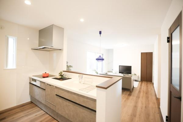 中鶴崎Ｗ　新築のキッチン|明るい照明と窓からの自然光がキッチン全体を爽やかに彩ります。カウンターが広く作業スペースもしっかりと確保されています。落ち着いた色合いのフローリングと調和したデザインが特徴です。