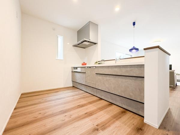 中鶴崎Ｗ　新築のキッチン|明るい照明と窓からの自然光がキッチン全体を爽やかに彩ります。カウンターが広く作業スペースもしっかりと確保されています。落ち着いた色合いのフローリングと調和したデザインが特徴です。