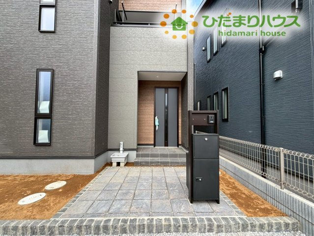 熊谷市万平町　第3　新築一戸建て　リーブルガーデン　02のエントランス|シックで上品な色合いの門柱と、木目調のドアが美しく調和する玄関アプローチです！ポーチ部分が広いため、来客時や宅配の対応もスムーズにできます◎