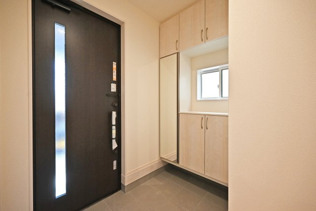 ブルーミングガーデン上甲東園5丁目新築一戸建て│3SLDK+駐車駐輪可の玄関|1階玄関をホール側から撮影した内観写真です。 シンプルな玄関扉にシューズボックス、小窓を配置したオーソドックスな玄関です。