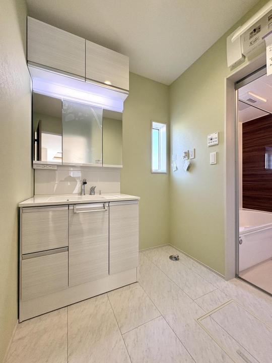 【Blooming Garden】東久留米市花小金井下里の洗面所|三面鏡付きで、朝の身支度もスムーズに。洗面化粧台上部と下部に収納を設け、収納力を確保。細々した小物は三面鏡裏にもしまうことができ、いつもすっきりとした状態に保つことができそうです。