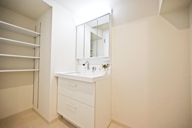 グランドハイツ甲陽園の独立洗面台|三面鏡タイプの洗面化粧台は、鏡裏に化粧品や整髪料のような小物を収納。洗面ボウル下に洗剤などの大きなものを収納できます。又、横には可動棚も設置してあるので荷物の大きさに合わせて収納できます。