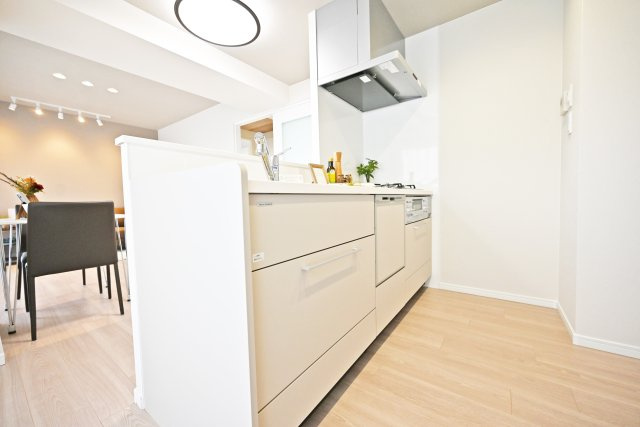 グランドハイツ甲陽園のキッチン|キッチン越しにダイニングを撮影した写真です。白色を基調としたキッチンは周囲の建具ともマッチしており空間の一体感を生んでいます。