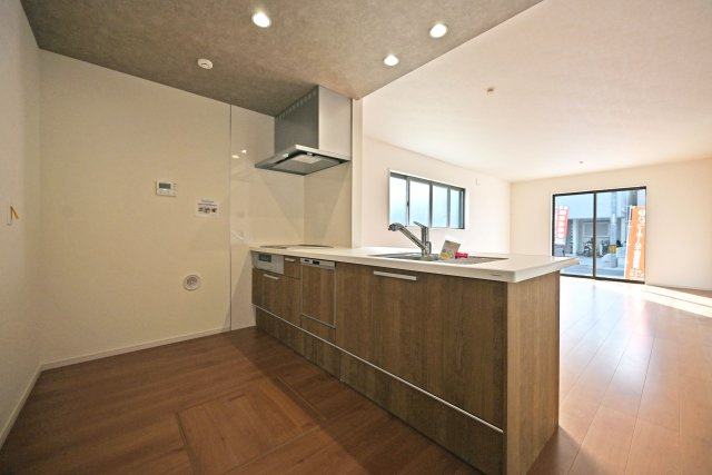 テラシエ食満3丁目新築一戸建て│4LDK+駐車並列2台可のキッチン|1階LDKをキッチン越しに撮影した現地内観写真です。 広くて使いやすいキッチンは折り下げ天井を採用しており、 オシャレな空間に仕上がりました。