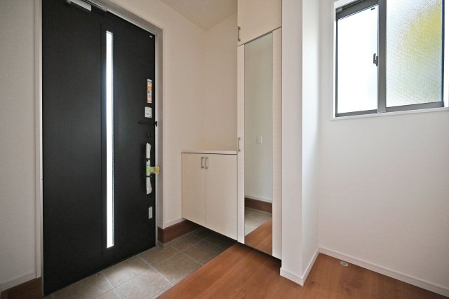 テラシエ食満3丁目新築一戸建て│4LDK+駐車並列2台可の玄関|1階玄関をホール側から撮影した内観写真です。 シンプルな玄関扉にシューズボックス、小窓を配置したオーソドックスな玄関です。