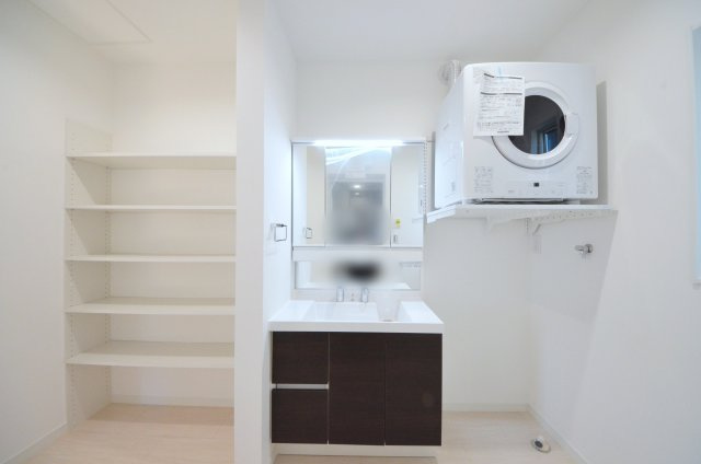桜尾三丁目の収納|清潔感あふれるシャワー付洗面台と洗面室。
乾太くんと収納棚のある余裕のスペース。
窓もあり明るく通気も良いです
