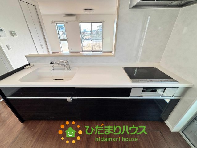 加須市南小浜　中古一戸建てのキッチン|シックなダークカラーのパネルが目を引くシステムキッチンです！広々としたシンクは大きな鍋も洗いやすく継ぎ目のないワークトップはお手入れも簡単。毎日のお料理がもっとスムーズに、もっと楽しくなりそうですね！