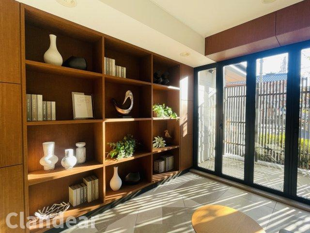 メイツ東綾瀬のロビー|木の質感が心地よい造作棚が印象的な共用スペース。さりげなく飾られた小物やグリーンから、住まう方を大切にする想いが伝わる、温かみあるアットホームな空間です