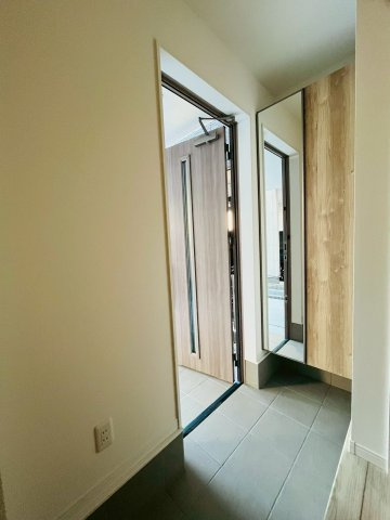 【玄関】 | 東淀川区北江口4丁目新築戸建 | 玄関ドアを開けると、温もりのある木目のシューズボックスがお出迎え。鏡付きでお出かけ前の全身チェックも！