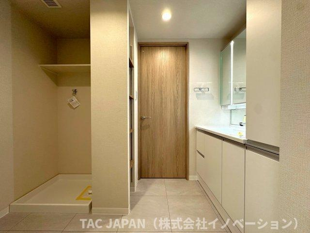 ジェイパーク北千住モナクレイスの洗面所|大型の洗濯機を置いても余裕が感じられる脱衣スペースにはお洒落な洗面ユニットを制作。着替えやタオル、洗剤の買い置きなどリネン庫の使い方はお客様しだい。