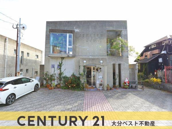 八幡店舗付中古の外観|シンプルで洗練されたデザインの外観が特徴的です。ゆとりある駐車スペースが確保され利便性も感じられます。グリーンに囲まれたエントランスで温かみを演出しています。