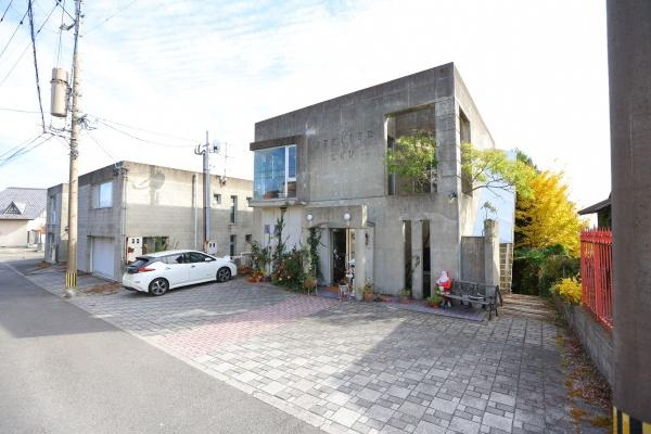 八幡店舗付中古の駐車場|広々とした駐車場が建物のすぐ前に配置されています。車の出し入れがしやすい設計です。舗装されたスペースがあり複数台の駐車にも対応できます。建物へのアプローチもスムーズな印象です。