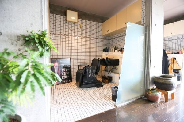 八幡店舗付中古の内装|白いタイル張りの壁と床が印象的な洗面スペースです。収納力のある吊り戸棚が備わっておりすっきりとした印象です。ガラス製の仕切りが空間を引き締めています。