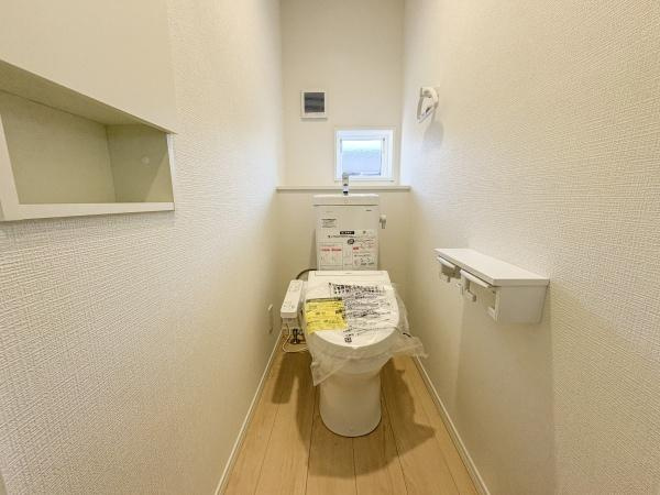 松が丘第1-1号棟のトイレ|トイレは白を基調としたシンプルな空間です。備え付けの棚やペーパーホルダーも完備されています。小窓があり自然光も取り入れられます。清潔感のある印象です。