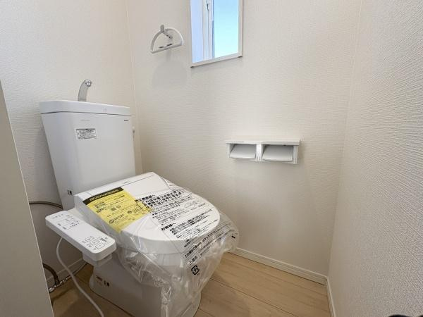 松が丘第1-1号棟のトイレ|窓が付いており換気に便利なトイレです。ペーパーホルダーが2連仕様になっています。壁や床の色合いが明るく空間がすっきりとしています。温水洗浄便座が設置されており使いやすさに配慮されています。