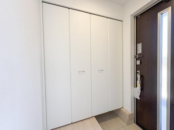松が丘第1-1号棟の玄関|玄関には大容量の収納スペースが設けられておりすっきりとした印象です。白を基調としたデザインが空間を明るく見せます。段差のある設計で使い勝手にも配慮されています。