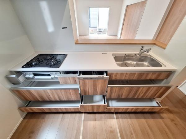 大在北3丁目2期2号棟のキッチン|シンプルなデザインが特徴のキッチンです。収納スペースが豊富で整理がしやすく、ガスコンロとシンクレイアウトは使い勝手を考えた設計です。木目調の扉が空間に調和しています。
