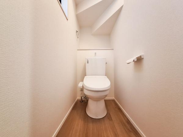 横塚2丁目1期2号棟のトイレ|壁や床材がシンプルで落ち着いた印象のトイレです。上部の窓から自然光が入りやすいデザインになっています。天井の形状も特徴的で空間を有効に活用しています。清潔感のある空間となっています。