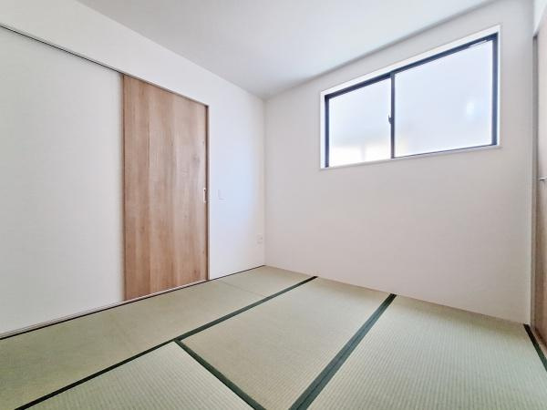横塚2丁目1期2号棟の和室|明るい窓から自然光が差し込むシンプルな和室です。ナチュラルな木目の扉が空間に統一感を与えています。落ち着いた雰囲気の畳が部屋全体の印象を引き締めています。