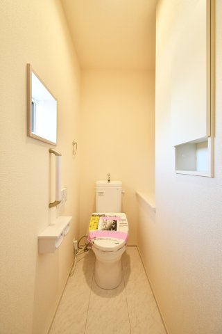 蓮田市椿山2丁目6期全1棟のトイレ|清潔感あふれる空間には、便利な壁面収納と手すり付き。窓からの採光で明るく、予備のペーパーもスッキリ収まります。毎日使う場所だからこそ、細やかな配慮と快適さを追求した安心のデザインです。