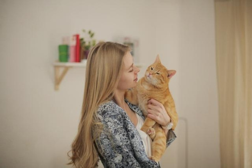 茶色い猫を抱える金髪の女性の写真