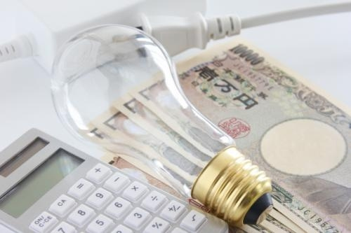 電球とコンセントと電卓とお札の写真